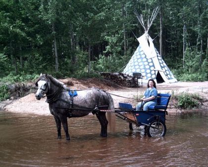 Voiture attelée dans la rivière devant un tipi